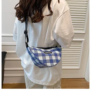 Close-up of blue checkered canvas crossbody bag with Fashion logo on a model