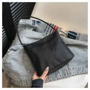 Detail of black nylon shoulder bag featuring embossed lettering and round handle on denim