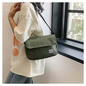 Detailaufnahme der dunkelgrünen Kuriertasche mit weißem Webetikett auf der Vorderklappe