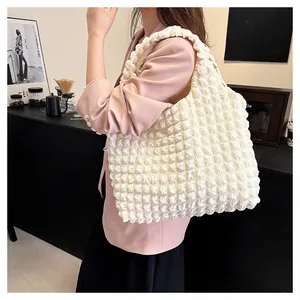 Détail du sac cabas blanc à texture nuage avec tissu gaufré sur l'épaule du mannequin