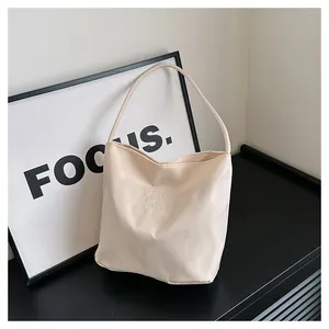 Macro detail of beige nylon handbag featuring white letter embroidery and premium texture