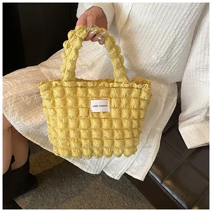 Detailed close-up of yellow bubble textured tote bag with love fashion woven label