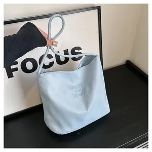 Close-up of light blue nylon bag with 'pretty and libety' embroidery and soft handle