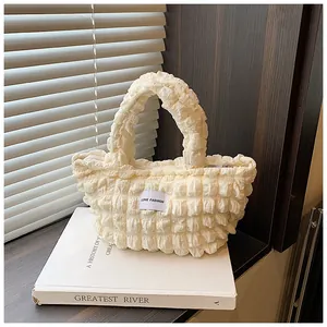 Close-up of cream pleated bubble bag with LOVE FASHION label on white book