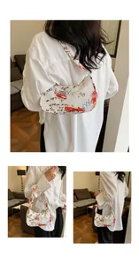 Detail view of white underarm bag featuring street style graffiti prints and crescent shape