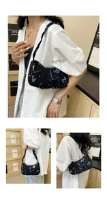 Detail of black underarm bag with blue and white abstract letters and zipper closure