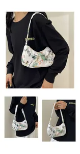 Detailed view of white canvas shoulder bag featuring artistic graffiti and zipper closure