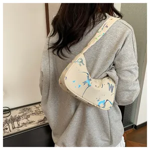 Detail of cream crescent shoulder bag with colorful ink splash and letter patterns