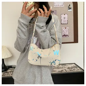 Detail of off-white crescent underarm bag featuring blue splatter print and metallic zipper