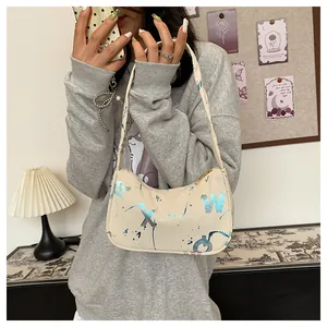 Detail view of cream underarm bag featuring blue artistic lettering and paint splatter