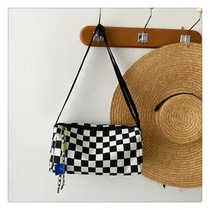Detail of checkered canvas crossbody bag with SORAKA blue tag and cord pendant