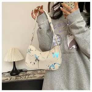 Detail of cream shoulder bag featuring blue abstract lettering and splatter art design