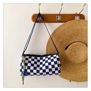 Close-up of blue checkerboard canvas bucket bag with fluorescent green woven keychain