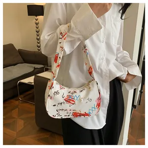 Detail of white graffiti print shoulder bag featuring artistic text and red color blocks