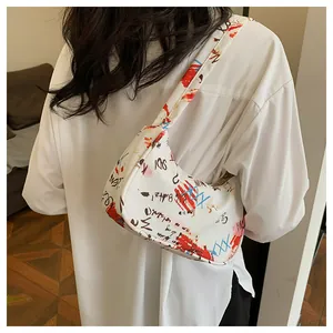 Detail view of the white leather underarm bag with artistic graffiti print and strap