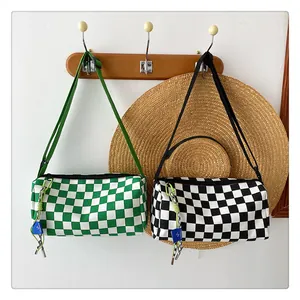 Detail of canvas checkerboard cylinder crossbody bags hanging on wooden hooks
