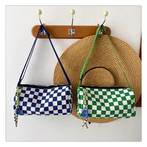 Detail of cylindrical checkerboard canvas bags in blue and green with woven strap charms