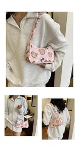 Dettaglio della borsa rosa sottobraccio con motivi di orsi cartoon e pois