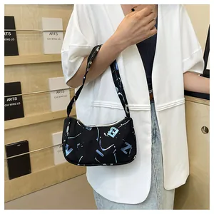 Close-up of a black crescent shoulder bag with artistic blue and white letter graffiti print
