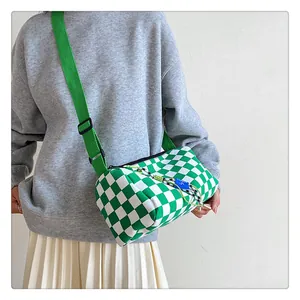 Detailed macro view of the green checkerboard canvas cylinder bag with blue tag