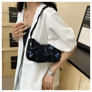 Detail of black canvas underarm bag with blue graffiti print worn with white blazer