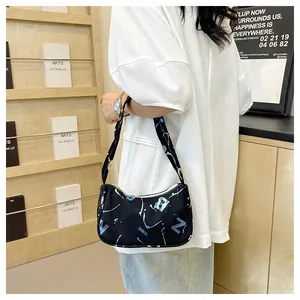 Detail shot of a black canvas underarm bag featuring blue and white graffiti art and wide strap