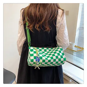 Detail view of green and white checkerboard canvas crossbody bag with adjustable strap