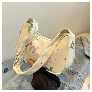 Detail of white canvas underarm bag with metallic colorful letters and splash pattern