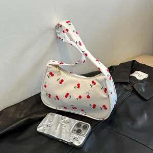 Detailed view of white canvas shoulder bag with cherry print and golden zipper closure