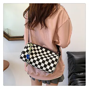 Detail of checkered canvas crossbody bag featuring side zipper and brand tag detail