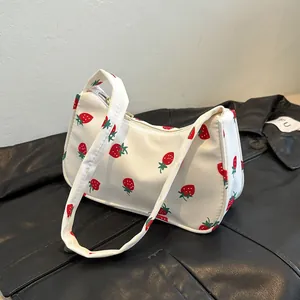 Detail shot of a white canvas shoulder bag with strawberry print on black leather jacket