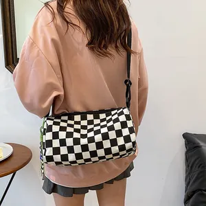 Checkboard canvas crossbody bag with adjustable strap and green rope detail on model