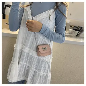 Close-up of a pink mini crossbody bag with a silver bow buckle and delicate chain strap