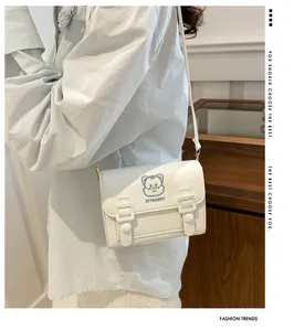 Detailed view of white PU crossbody bag with blue cat embroidery on blue shirt