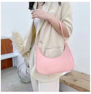 Minimalist pink crescent nylon underarm bag worn on shoulder by model in elegant setting
