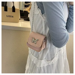 Detailed side view of mini pink crossbody bag with silver bow accent and metal chain strap