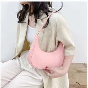 Pink crescent underarm bag shown on shoulder in a minimalist fashion lifestyle setting