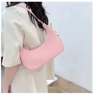 Side view of a pink crescent hobo bag worn by a model against a minimalist background