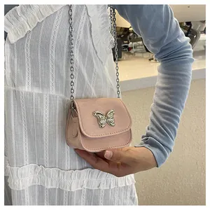Close-up of a mini pale pink crossbody bag with a silver butterfly and chain strap
