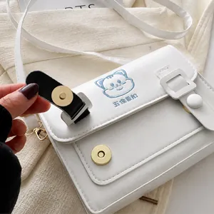 Detail of the metal magnetic buckle on a white PU leather crossbody bag for girls
