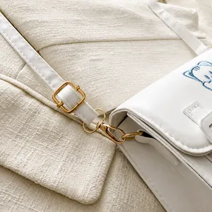Close-up of adjustable shoulder strap with gold metal buckle on white cartoon cat bag