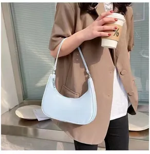 Detail of light blue crescent underarm bag worn with a casual brown blazer