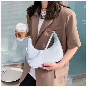 Detail of light blue crescent hobo bag worn by a model in a modern urban setting