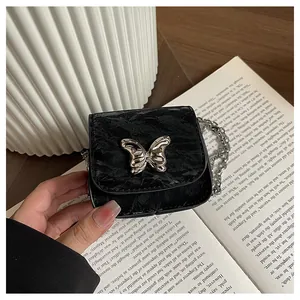 Close-up of black velvet mini bag with silver bow clasp and elegant chain strap