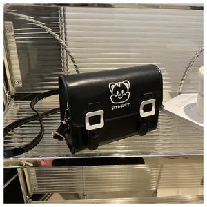 Detail of black PU leather messenger bag with cute cat embroidery and white square buckles
