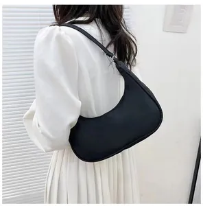 Minimalist black crescent shoulder bag shown on model with smooth finish and silver rings