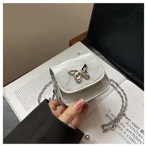 Detail of silver mini bow handbag with textured metallic finish and elegant chain strap