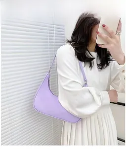 Lavender crescent underarm bag shown on model wearing white dress in bright setting