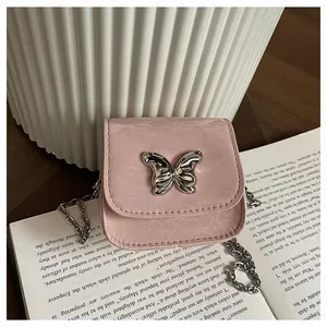 Detail of pink mini crossbody bag with silver butterfly ornament and metal chain