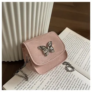 Detailed view of pink textured leather mini bag with silver bow ornament on a vintage book